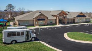 Daycare bus, metal awning, decorative gable trim, cherokee brick, Sherwin William quiver tan, Sherwin Williams tony taupe, daycare design, day care center design, childcare design, child care design, child care centre design, child care interior design, child care architect